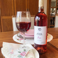 Botella y copa de vino rosado Vinícola Diez Gonzáles Orgullo y prejuicio en fondo de madera